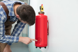 Worker check specification of a wall mounted Fire Extinguisher