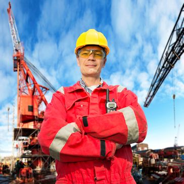 Worker standing in front of heavy machinery with PPE