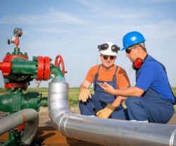 Wto workers consulting one another in front of pipe