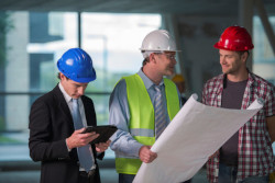 Three workers looking a blueprints for a pre-bid meeting