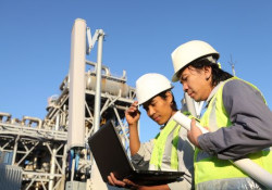 Two workers looking at a laptop standing outside in front of work site