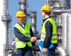 Two workers shaking hands in agreement in front of worksite