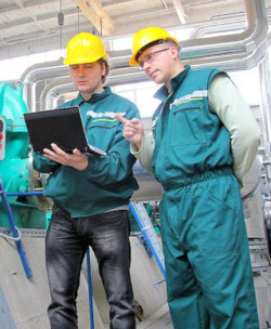 Two men looking up information on laptop computer while inspecting for safety