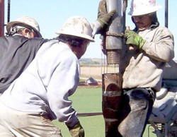 Three workers outside working around large pipe