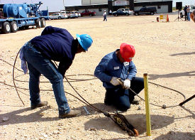 Two workers setting up service rig guy lines