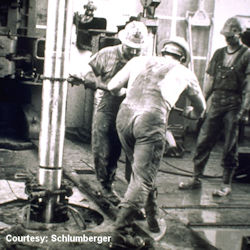 Image of roughnecks using chain tong to tighten a pipe