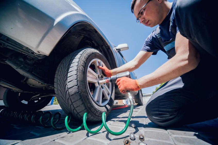 Worker using air tool to check car tire