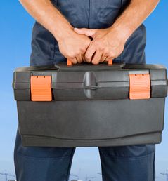 A worker standing holding a tool box