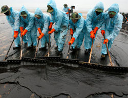 Image of line of workers dressed in PPE surrounding oil spill