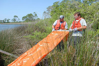 Two workers deploying a containment boom