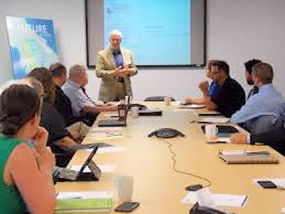 Management speaking to a group employees sitting around a conference table